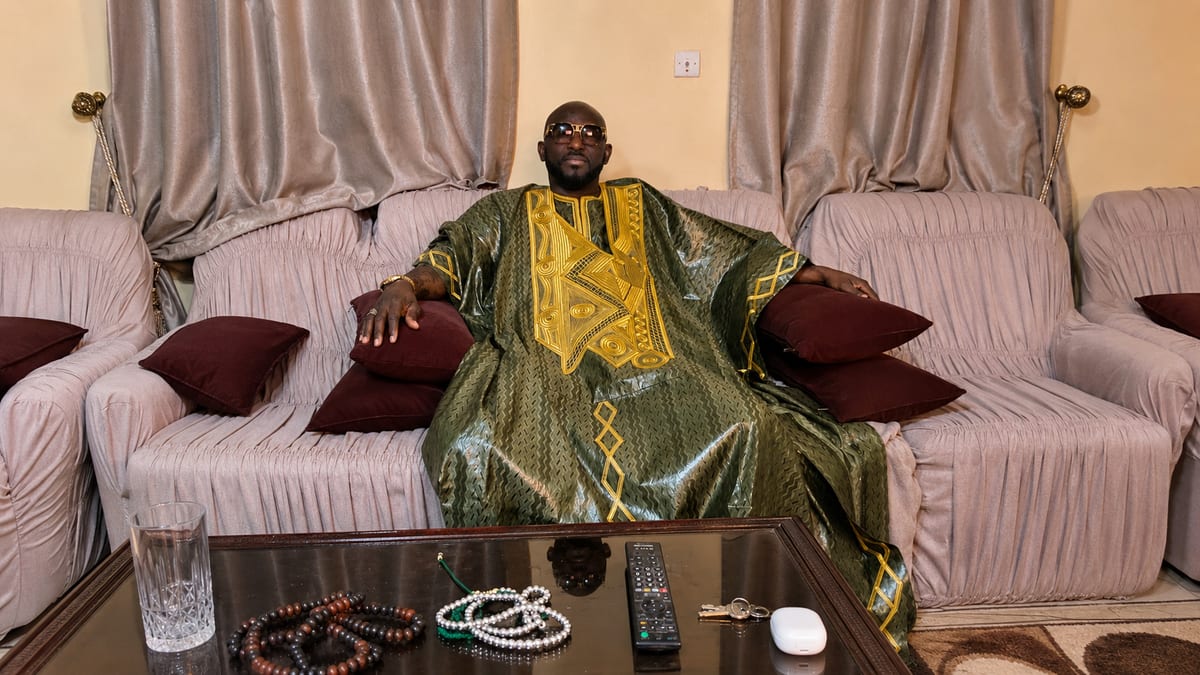 Marabout Djibril en boubou vert et or, chapelets posés devant lui