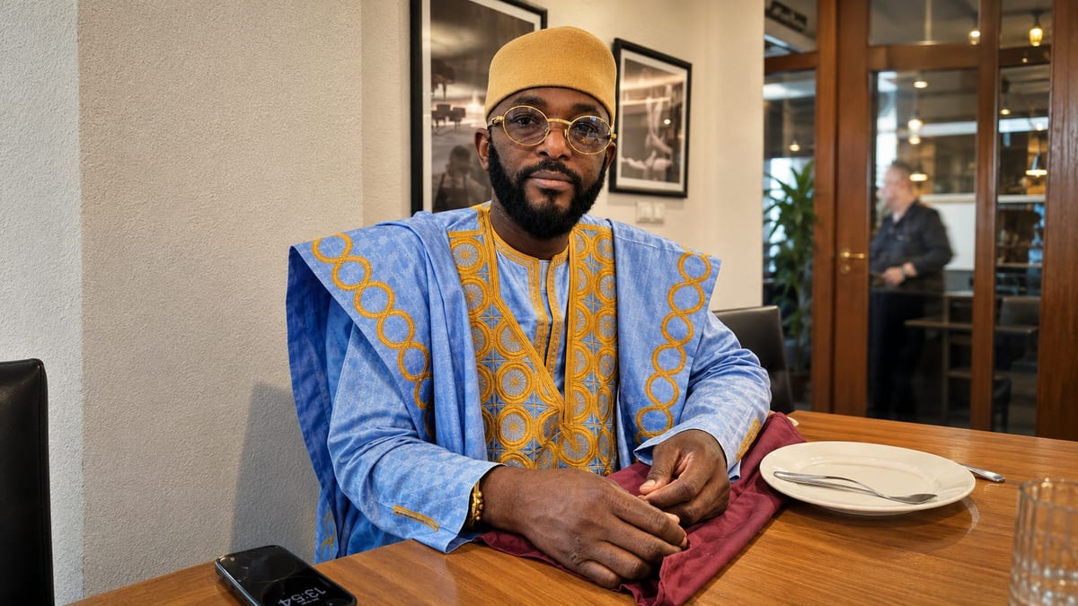 Marabout Djibril en boubou bleu et or, attablé en consultation